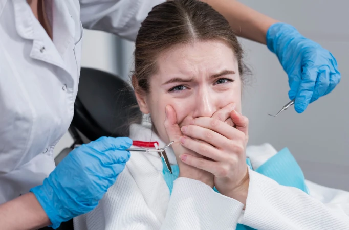 Anxious young woman covering her mouth while sitting in a dental chair during a dental appointment