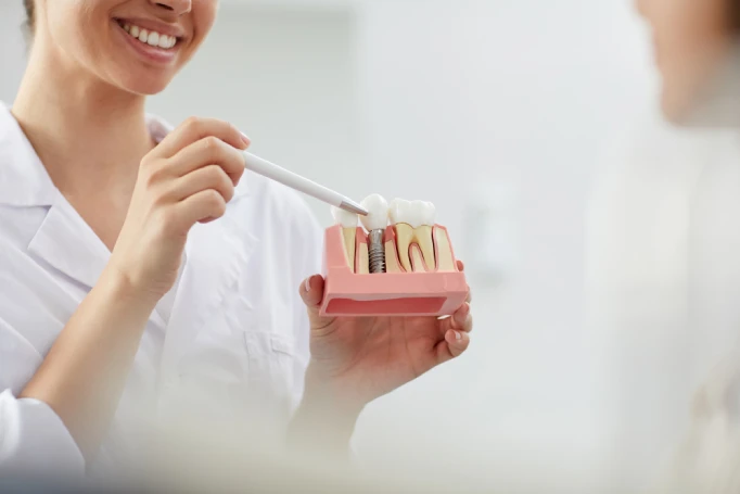 Smiling dentist explaining dental implant treatment options during a consultation